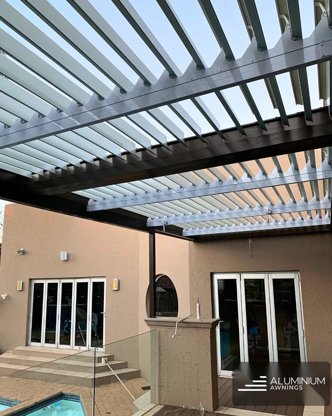 Manual louvre roof in bronze frame with white louvre panels — Bellville, Cape Town Northern Suburbs