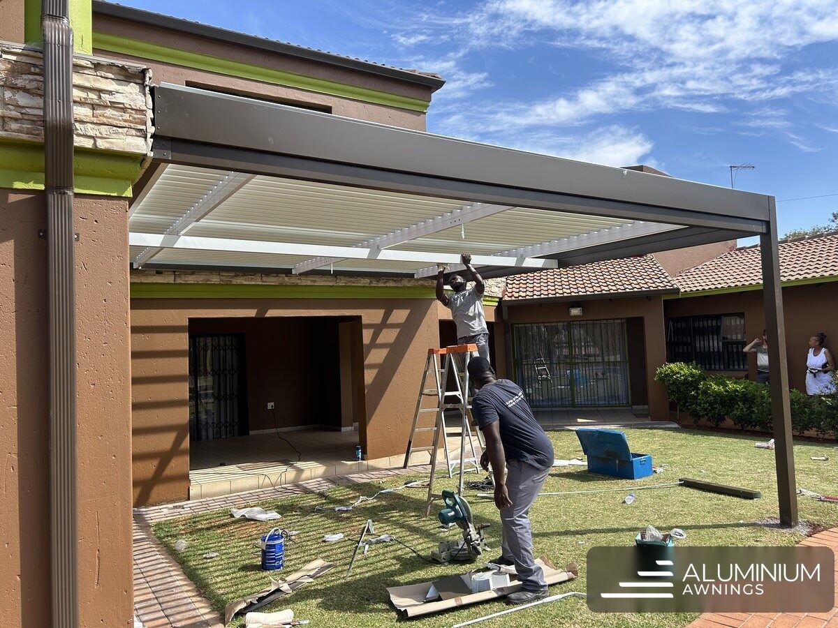Aluminium Awnings team fitting the white louvre blades into the bronze frame in Hermanus.