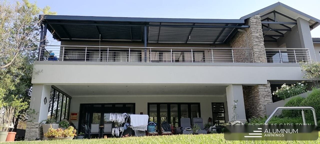 Charcoal aluminium louvre roof spanning the upper-floor terrace of a double-storey Plattekloof home.