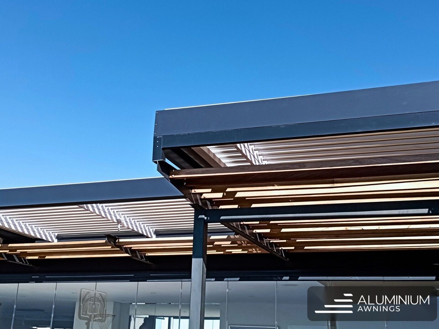 Dark-framed twin-bay aluminium louvre pergola under a deep blue Cape Town sky